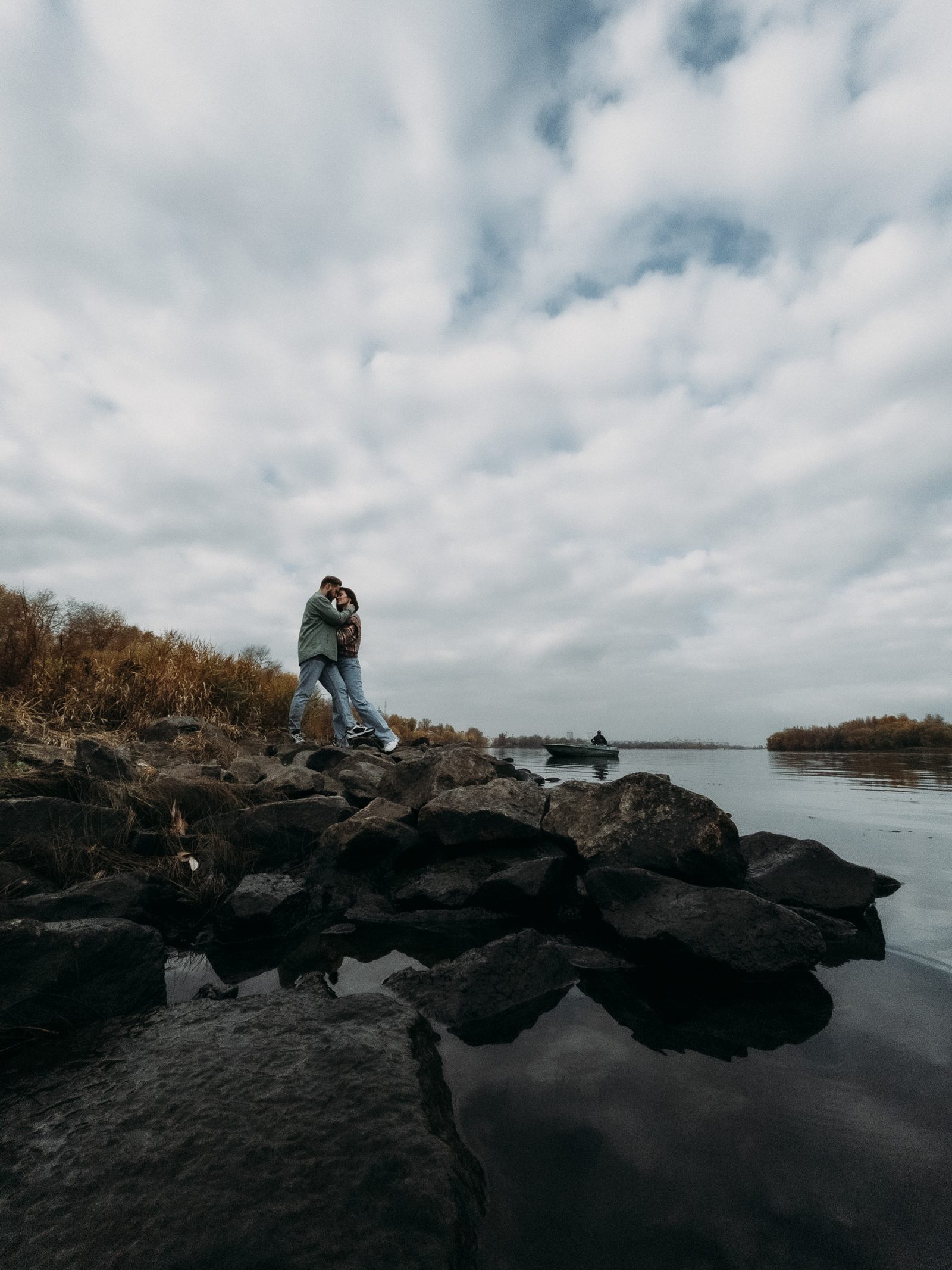 Love couple embrace rocky riverbank wide landscape