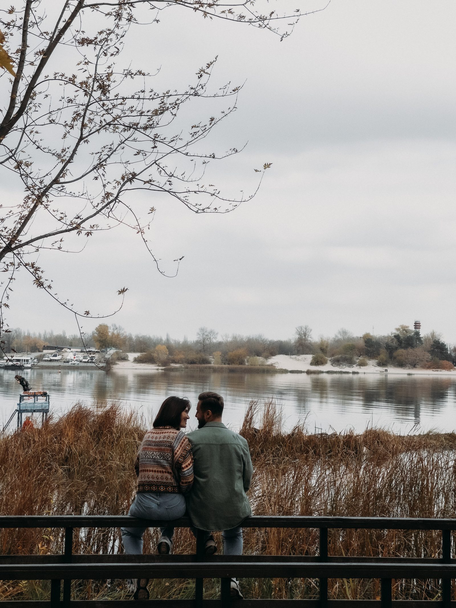 Love couple sitting railing lake view portrait