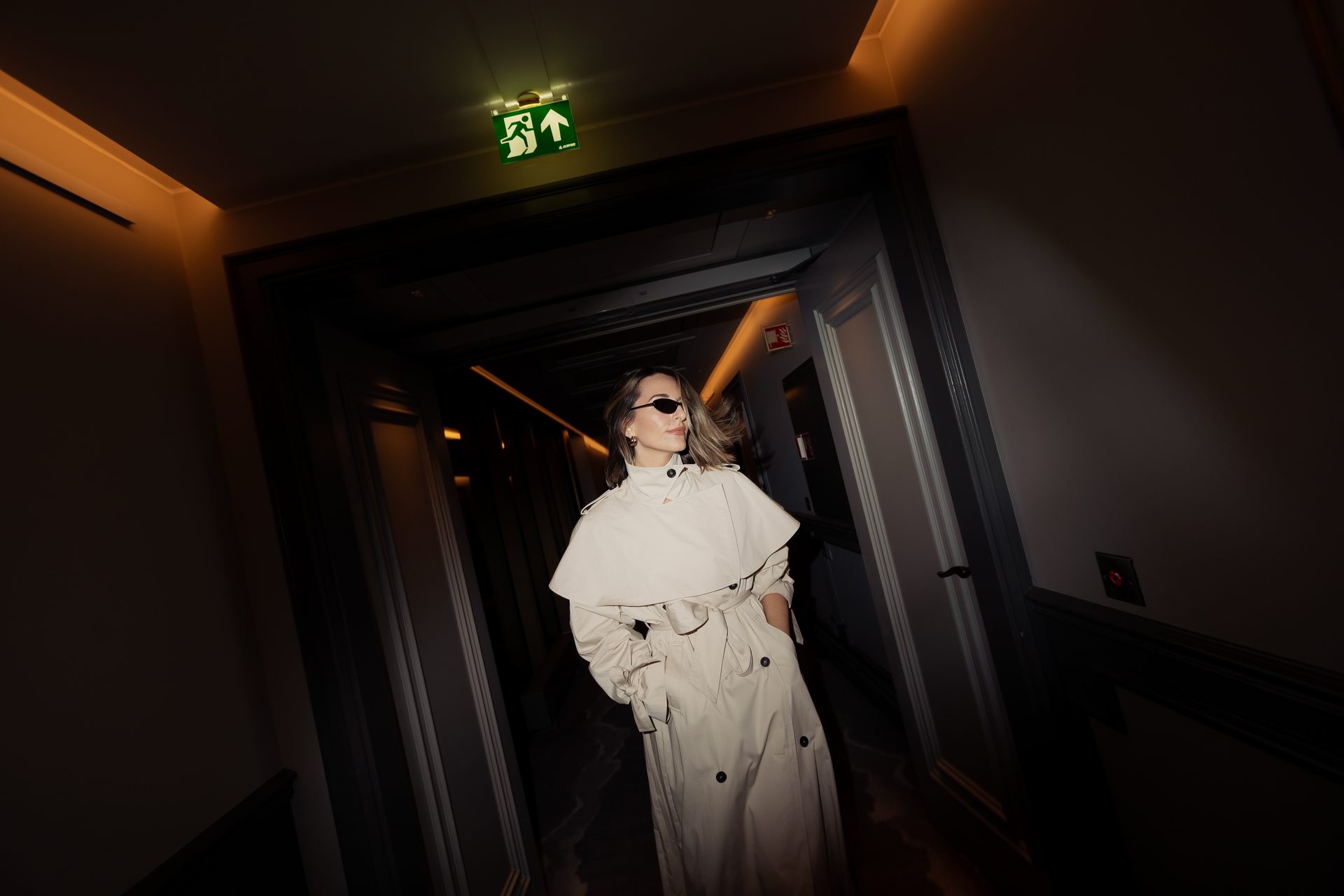 Sara cream trench dark hallway exit sign editorial